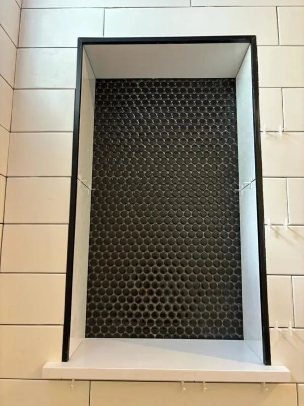 Black mosaic shower niche and white wall tile